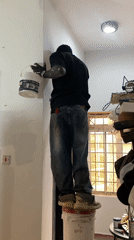 Man paints walls white using paint buckets in Jos home