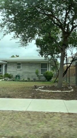 The video shows a car driving through a neighborhood on an overcast day.  Several ranch style houses with dry, patchy lawns are visible.  In one driveway there is a black pickup truck and a white BMW SUV.  Another shot includes the grill of a white Ford F250.