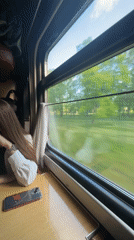 Train passenger rests by window during early morning journey in Minsk