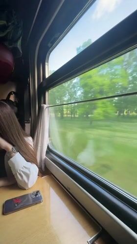 Train passenger rests by window during early morning journey in Minsk