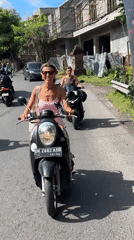 Woman in pink dress rides scooter in North Kuta