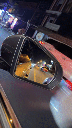 Nighttime traffic observed through car mirror in Thailand