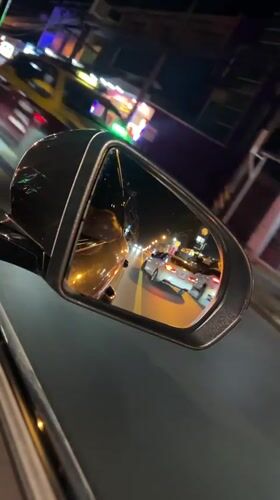 Nighttime traffic observed through car mirror in Thailand