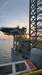 Offshore supply vessel operates near drilling platform at Italian sunset