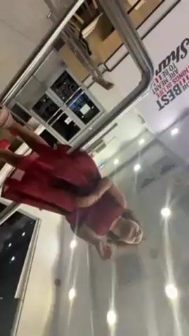 A person in a red dress is being recorded inside a building that seems like an upscale mall or a store. The camera angle is unusual, looking up at the person through a transparent barrier, possibly part of an exhibit or attraction. The person is waving and saying, "Goodbye, good luck." The background shows a well-lit interior with various display units and lighting fixtures.