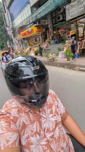 Motorcyclist rides blue Honda through busy Dhaka street
