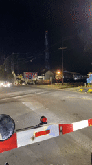 Train crosses through Madiun intersection as gates lower, traffic waits