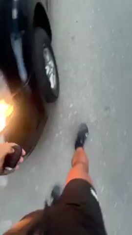 A person walks up to a black car and opens the driver's side door. They then get inside the car and presumably start it. The video is shot from the perspective of someone inside the car.