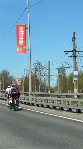 Three cyclists cross bridge in sunny Lisy Nos