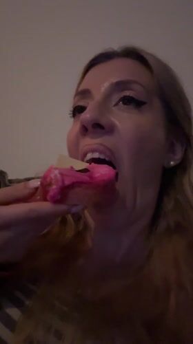 Woman enjoys pink-frosted donut in Amsterdam