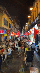 Crowded nighttime street scene with dining in Hanoi alleyway