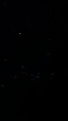 The video shows a very dark scene, likely indoors, with some faint outlines of what appears to be stage equipment. It is so dark that very little detail is discernible. The only activity is the sound of clapping.