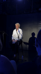 Reading from a book on a bare stage in Los Angeles