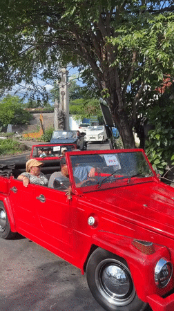 Red Volkswagen convoy drives through Denpasar morning traffic