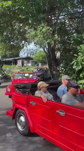 Red Volkswagen convoy drives through Denpasar morning traffic