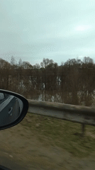Car window view captured in Kremyonki showing guardrail, water