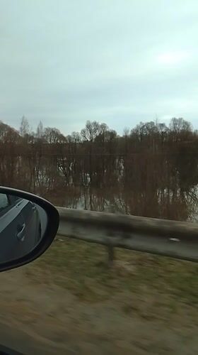 Car window view captured in Kremyonki showing guardrail, water