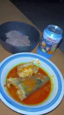 A plate of what appears to be fish stew with a vibrant red sauce is presented on a table next to a bowl of ground substance, possibly meat. A can of Chivita Active Zest C sparkling fruit drink is also visible. The camera angle varies slightly, providing close-ups and a wider view of the food arrangement.