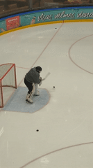 Hockey goalie stands ready in net with two pucks