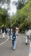 Group with backpacks walks tree-lined road in Chongqing