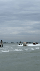 Three motorboats navigate Venice channel under grey skies