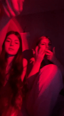 Two women observed in red-lit indoor setting