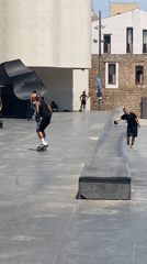 Skateboarders perform tricks in Barcelona plaza during midday session