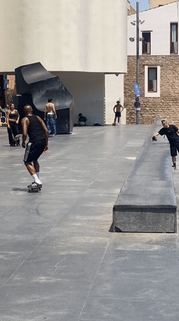 Skateboarders perform tricks in Barcelona plaza during midday session