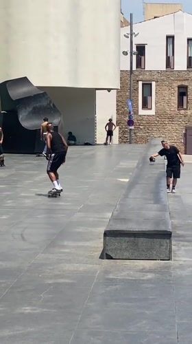 Skateboarders perform tricks in Barcelona plaza during midday session