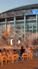 Evening plaza scene outside a Moscow stadium with fountains