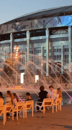Evening plaza scene outside a Moscow stadium with fountains