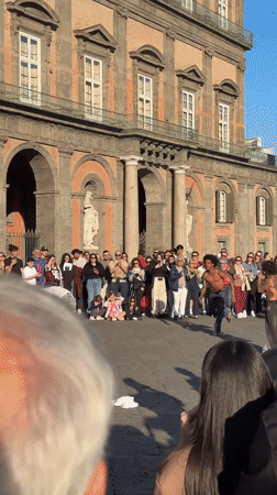 Skateboarder performs tricks for crowd in Naples plaza