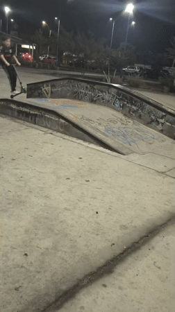 Youth rides scooter at nighttime skate park in Arica