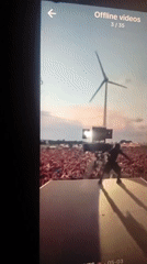 Stage performer silhouetted against sunset with wind turbine backdrop