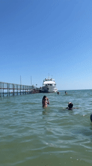 Sunny morning at Rimini's pier: yachts docked, swimmers in the Adriatic