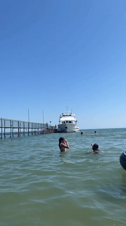 Sunny morning at Rimini's pier: yachts docked, swimmers in the Adriatic