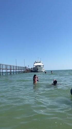 Sunny morning at Rimini's pier: yachts docked, swimmers in the Adriatic