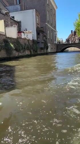 Canal boat tour carries young passenger through sunny Bruges