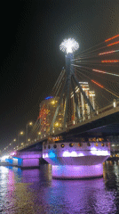 Illuminated boats cruise under lit bridge in Đà Nẵng
