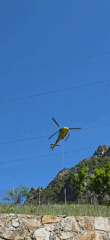 Yellow helicopter with suspended rope flies near powerlines in Spain