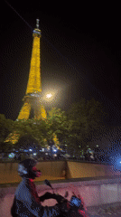 Motorcyclist stops at red light near illuminated Eiffel Tower