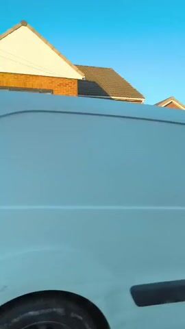 This media file is a video showing a street view of a residential area. The camera appears to be moving, possibly from a vehicle, as the scene pans across a row of houses. The houses are primarily brick-built, typical of suburban architecture in the United Kingdom.

**Subjects:**
The main subjects are the houses and the cars parked in their driveways. There are no people visible in the video. Objects include cars, garages, garden hedges, a brick wall, and a chimney.

**Activity or Event:**
The video captures a continuous visual sweep of the street, suggesting a drive-by or a slow movement along the road. No specific event is taking place other than the observation of the residential environment.

**Notable Details:**
- **Time of Day:** The lighting suggests it is late afternoon or early evening. The sun is low in the sky, casting long shadows and highlighting the facades of the houses with a warm glow. The sky is clear and blue, indicating fair weather.
- **Location Cues:** The architecture of the houses, the cars, and the general streetscape are consistent with a suburban area in the United Kingdom, specifically Sandwell.
- **Emotions:** The media file does not convey any explicit emotions. It is a neutral observation of a neighborhood.

**Visible Text:**
Several license plates are visible on the cars:
- "AU64 LTN"
- "CR16 UDL"
- "KM62 HXH"

One house number is visible: "45A".

The overall impression is a calm, everyday view of a residential street bathed in the golden light of the setting sun.