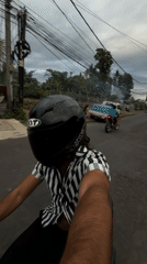 Motorcyclist rides red scooter through Mengwi street