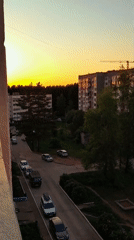 Residential street captured at sunset with moving traffic