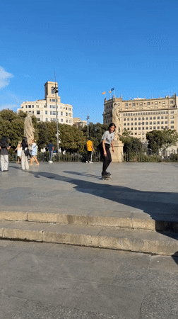 Woman performs skateboard ollie trick in Barcelona plaza