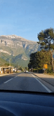 Vehicle travels paved road in Kavač, Montenegro under clear skies
