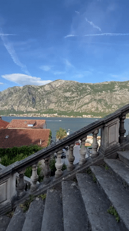 Young couple photographs scenic Bay of Kotor from Montenegro balcony