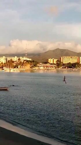 Sunset over Juan Griego's bay, boats, and rocky coast