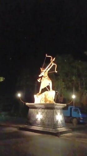 Golden warrior statue illuminated at night in Chopdem, India