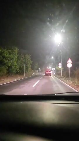 The video shows a car driving on a road at night. The road is wet, suggesting it has been raining. There are streetlights and road signs visible. The car in front has its brake lights on. The license plate of the car in front is visible and appears to be B 5231 BH. The car appears to be a silver Citroen C4.